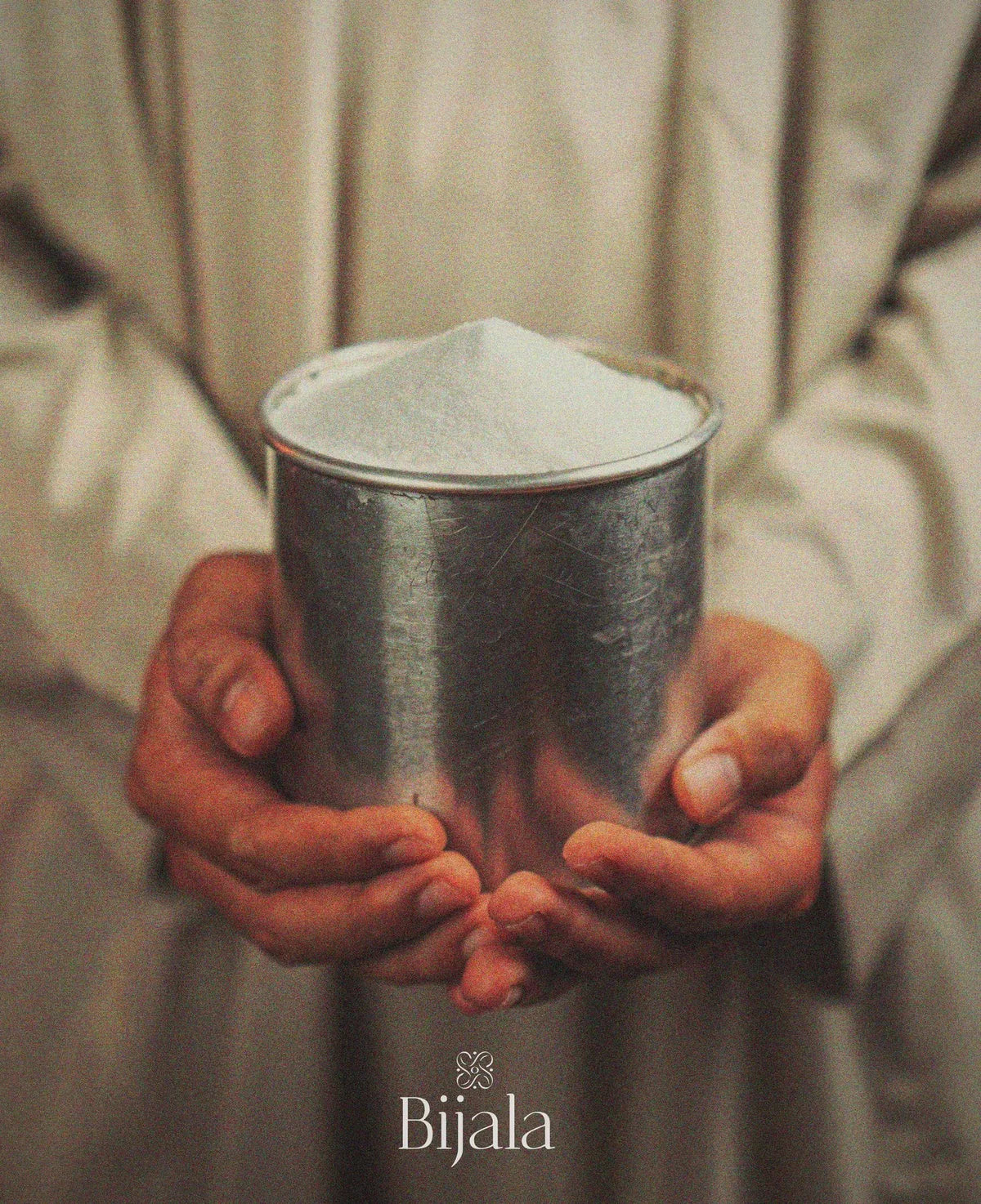 Hands holding the vessel of blessed mandala sand passed to Bijala
